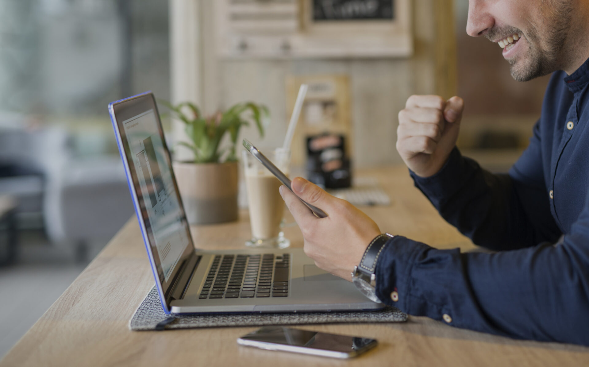 Happy freelancer with tablet and laptop computer in coffee shop